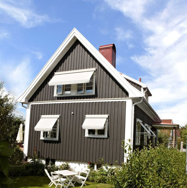 Hvite markiser på mørkegrått hus, med hage forgrunnen