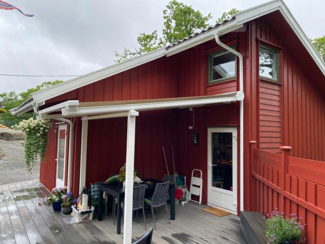 Pergola over inngang til rødt hus