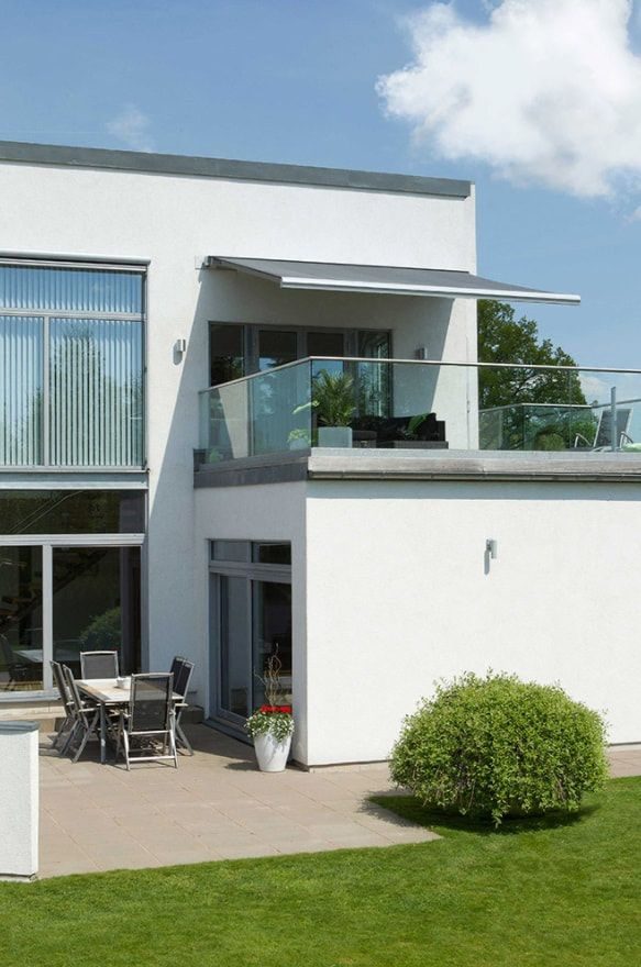 Moderne hvitt hus med markise hengende over terasse