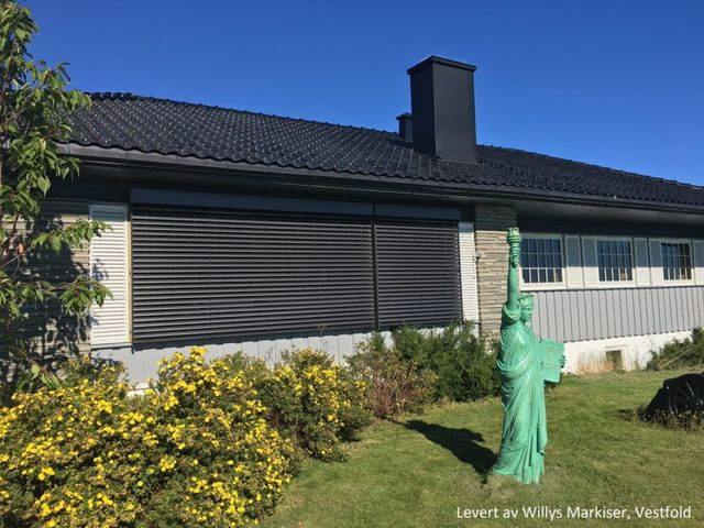 Persienner foran vinduer med grønn statue i forgrunn